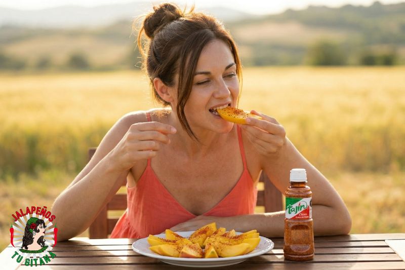 Mujer comiendo mango fresco con especias en un día de verano
